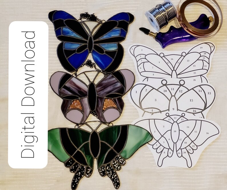 May include: Three stained glass butterfly patterns with numbered sections for a craft project. The patterns are printed on white paper and include numbers 1 through 26.