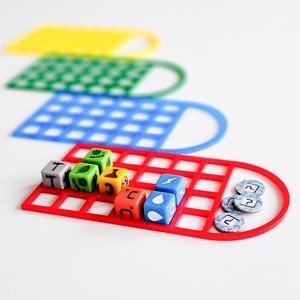 May include: A red game board with a grid of squares and a set of colorful dice with symbols. The dice are arranged in a row on the board. There are also several small blue tokens with question marks on them.