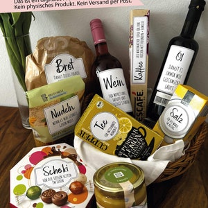 Puede incluir: Una cesta de mimbre llena de varios artículos de comida, que incluyen pan, pasta, vino, té, café, aceite, sal, chocolate y miel. Los artículos están etiquetados con palabras alemanas, como "Brot" para pan y "Wein" para vino.