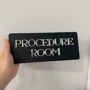 Op de afbeelding: Een zwart bord met zilveren letters met de tekst "PROCEDURE ROOM".