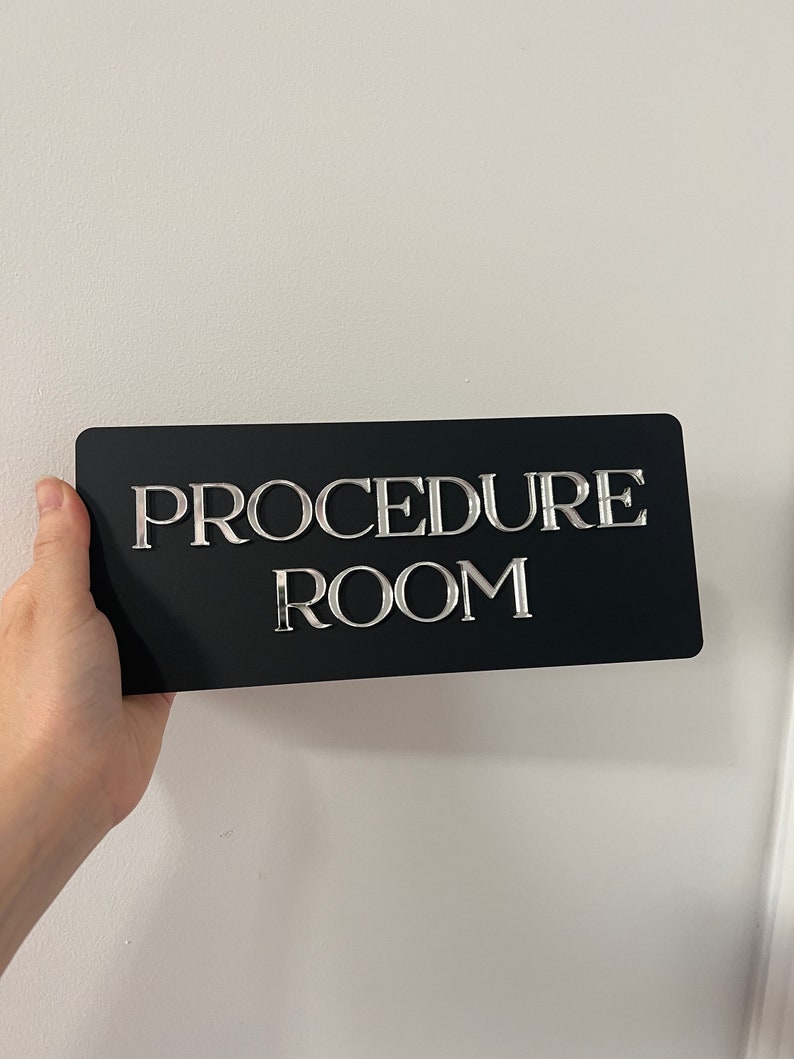 Op de afbeelding: Een zwart bord met zilveren letters met de tekst "PROCEDURE ROOM".