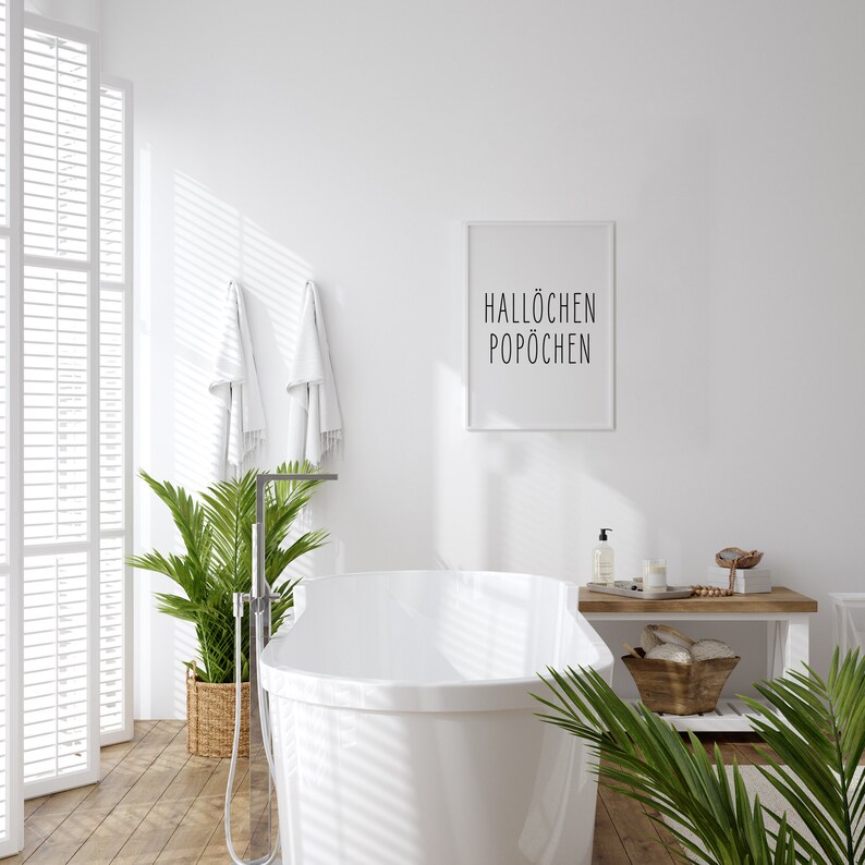 May include: A white bathtub with a chrome faucet and shower head, surrounded by plants and towels. A framed print with the text "Hallochen Pop&ouml;chen" hangs on the wall.