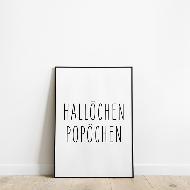 May include: A black framed poster with white background and the text "Hall&ouml;chen Pop&ouml;chen" in black.