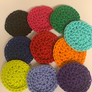 May include: Ten round crocheted coasters in various colors, including black, navy blue, green, turquoise, red, orange, yellow, light blue, and purple.