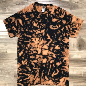 Puede incluir: Una camiseta negra con un patrón de tie-dye decoloración marrón.
