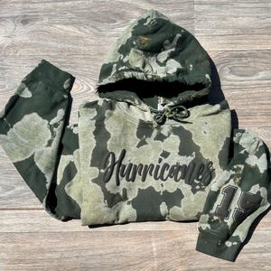 May include: Green and white tie-dye hoodie with black text that says "Hurricanes" and a black number "15" on the sleeve.
