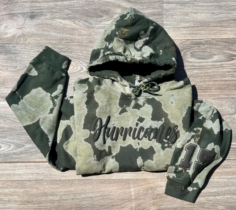 May include: Green and white tie-dye hoodie with black text that says "Hurricanes" and a black number "15" on the sleeve.