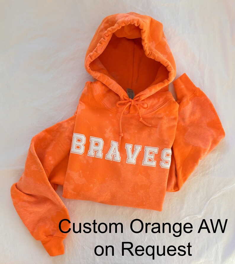 May include: Orange hoodie with the word "BRAVES" in white lettering. Custom orange tie dye available on request.