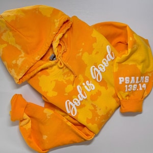 May include: A yellow tie-dye hoodie with the text "God is good" in white on the front and "PSALMS 139:14" in white on the sleeve.