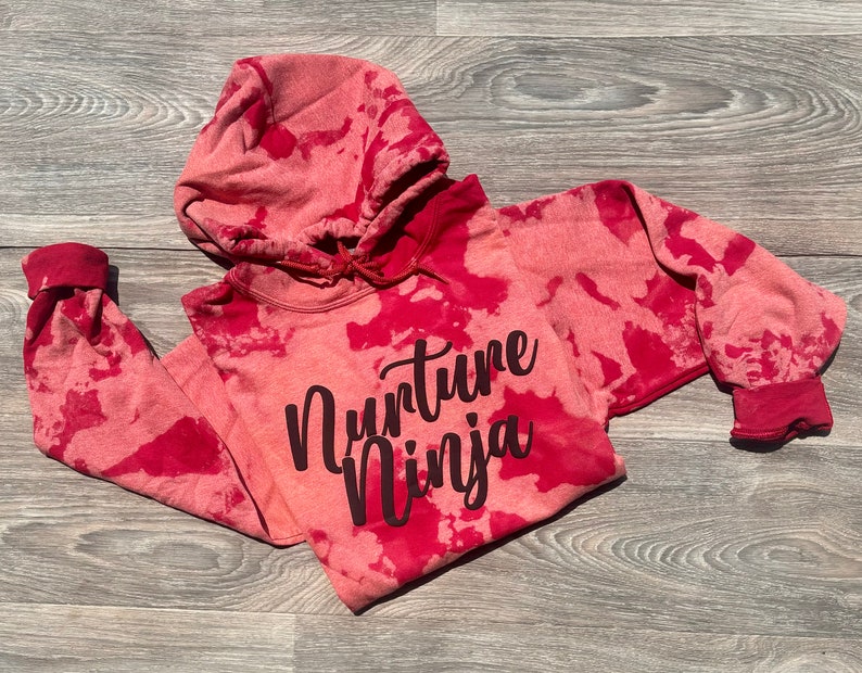 May include: Red tie-dye hoodie with the text "Nurture Ninja" in black lettering.