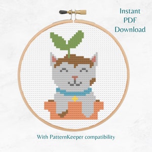 May include: Cross stitch pattern featuring a cute cat with a plant growing out of its head. The cat is wearing a blue collar with a yellow star. The pattern is in a round hoop and is available as an instant PDF download. It is compatible with PatternKeeper.