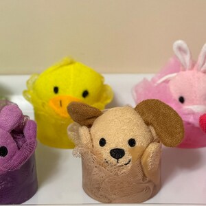 May include: Five colorful bath poufs shaped like animals. The poufs are green frog, yellow duck, purple bunny, brown dog, and pink cat.