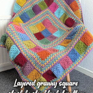 Op de afbeelding: Een kleurrijke granny square deken in tinten blauw, groen, geel, oranje, rood en paars, gedrapeerd over een stoel. De tekst "Layered granny square stash buster blanket pattern" is zichtbaar.