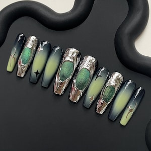 May include: A set of long, coffin-shaped false nails. The nails feature a gradient design, transitioning from dark green to light green. Some nails have silver metallic accents and a central green glitter design.