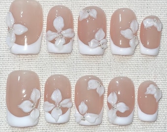 Uñas postizas cuadradas cortas con diseño de flor blanca y pétalos 3D blancos, ideales para bodas y cumpleaños. Diseño artesanal.