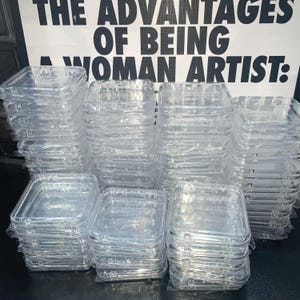 May include: A stack of clear plastic square containers. The containers are stacked on top of each other and are all the same size. The containers are made of a clear plastic material and have a smooth surface. The containers are empty and are ready to be used.