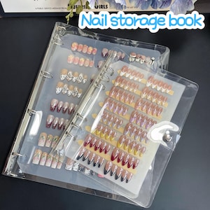 Könnte beinhalten: Ein transparentes Nagelaufbewahrungsbuch mit mehreren Seiten voller verschiedener künstlicher Nageldesigns. Die Designs umfassen Blumenmuster, Glitzer und Volltonfarben. Der Text "Nail storage book" ist auf dem Cover sichtbar.