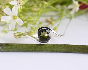 May include: A silver ring with a green gemstone set in a curved band.