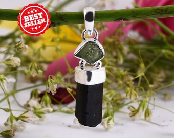 May include: A silver pendant featuring a black tourmaline crystal and a green aventurine stone. The pendant is hanging from a green stem.