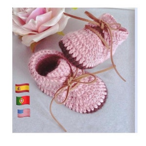 Puede incluir: Un par de botines de bebé de ganchillo rosa con cordones de cuero marrón. Los botines tienen un patrón de punto texturizado y un ribete marrón alrededor de los bordes.