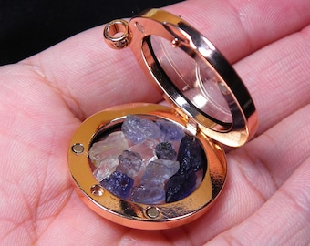 May include: A rose gold locket pendant with a clear glass lid, revealing a collection of small blue and clear crystals inside.