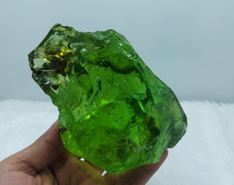 May include: A large, green, glass rock with air bubbles trapped inside. The rock has an irregular shape and is translucent.
