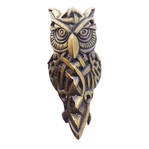 May include: A gold-colored metal owl sculpture with intricate Celtic knotwork designs. The owl's eyes are detailed and the sculpture has a three-dimensional appearance.