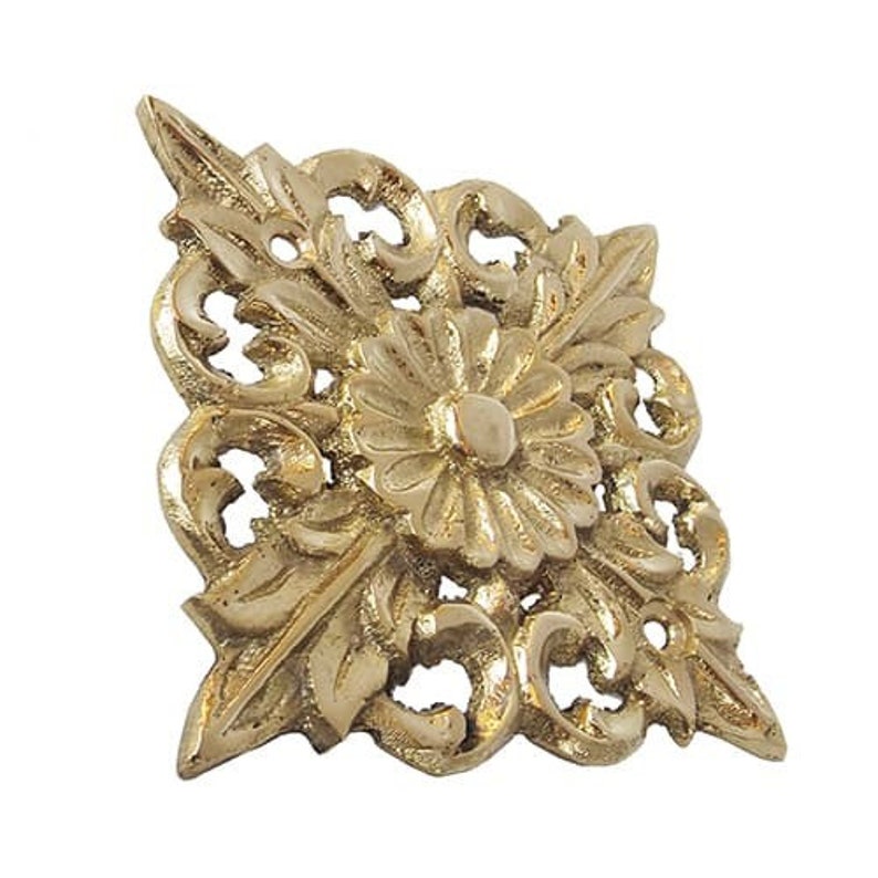 May include: A gold-toned metal decorative accent with a floral design. The accent features a central flower with intricate details and surrounding leaves.