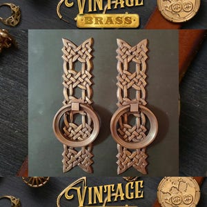 May include: Two vintage brass door pulls with a Celtic knot design and a ring handle. The pulls are a dark brown colour and have a distressed finish.