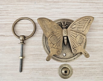 Puede incluir: Un llamador de puerta de latón con forma de mariposa, una placa trasera circular, un anillo de tracción circular separado con un perno roscado y una tuerca, y una pequeña pieza de montaje circular. Acabado metálico envejecido y detallado.
