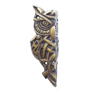 May include: A brass owl wall hook with intricate geometric designs. The owl's eyes are detailed and the hook is shaped like the owl's body.
