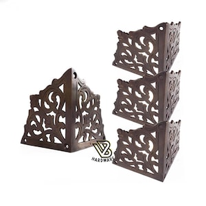 May include: Set of four ornate brass corner brackets with a decorative floral design. Each bracket is approximately 9 cm in size.