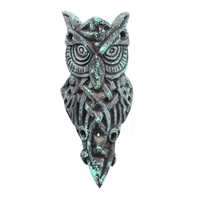 May include: A green and brown cast iron owl wall decor with intricate Celtic knotwork design. The owl has large, round eyes and a detailed beak.