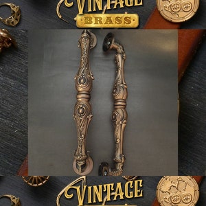 Pode incluir: Duas ma&ccedil;anetas de porta ornamentadas, de cor dourada, com desenhos intrincados. As ma&ccedil;anetas s&atilde;o de lat&atilde;o e t&ecirc;m um estilo vintage.