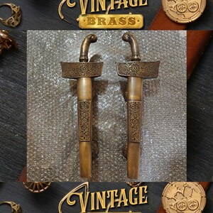 May include: A pair of ornate brass door handles in the shape of traditional Indonesian daggers. The handles feature intricate carvings and a gold finish.
