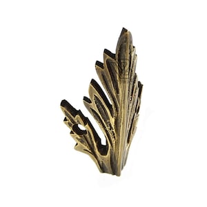 May include: A bronze-coloured, leaf-shaped decorative furniture applique. The metal leaf has intricate veining and a hole near the base. The leaf is angled slightly, showcasing its detailed design and texture against a white background.