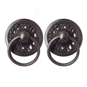 May include: Two antique bronze cabinet door pulls with ornate floral designs and a ring handle.