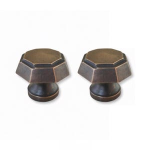 May include: Two bronze-colored cabinet knobs with an octagonal top and a round base. The knobs have a dark, aged finish, suggesting a vintage or antique style. The hardware is designed for furniture or cabinetry.