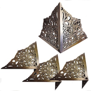 May include: Set of four ornate brass corner brackets with a floral design. The brackets are triangular in shape and have a decorative, intricate pattern.