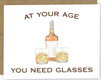 Pode incluir: Um cartão branco com texto castanho que diz "At your age you need glasses". O cartão apresenta uma ilustração de desenho animado de uma garrafa de uísque e dois copos de uísque.