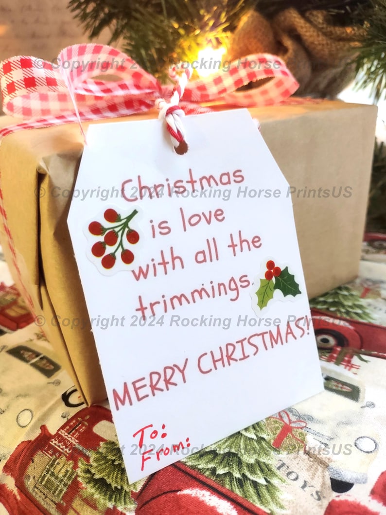 May include: White gift tag with red text that reads "Christmas is love with all the trimmings. Merry Christmas!"  The tag has a red and white gingham ribbon attached to it.  The tag is tied to a brown gift box with a red and white gingham bow.