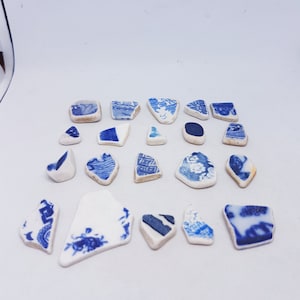 Könnte beinhalten: Eine Sammlung von blauen und weißen Keramikscherben mit komplizierten Mustern. Die Scherben sind in verschiedenen Formen und Größen vorhanden, und einige haben eine leicht erhabene Textur.