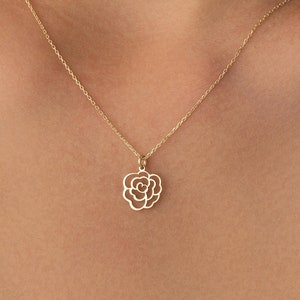 Op de afbeelding: Een gouden ketting met een delicate roos hanger.