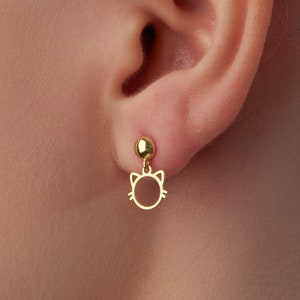 Op de afbeelding: Gouden oorbelletjes in de vorm van een kattenkop. De oorbelletjes zijn klein en delicaat, met een simpel kattenkopontwerp.