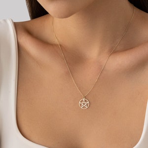 Op de afbeelding: Een gouden ketting met een hanger met een vijfpuntige ster in een cirkel.
