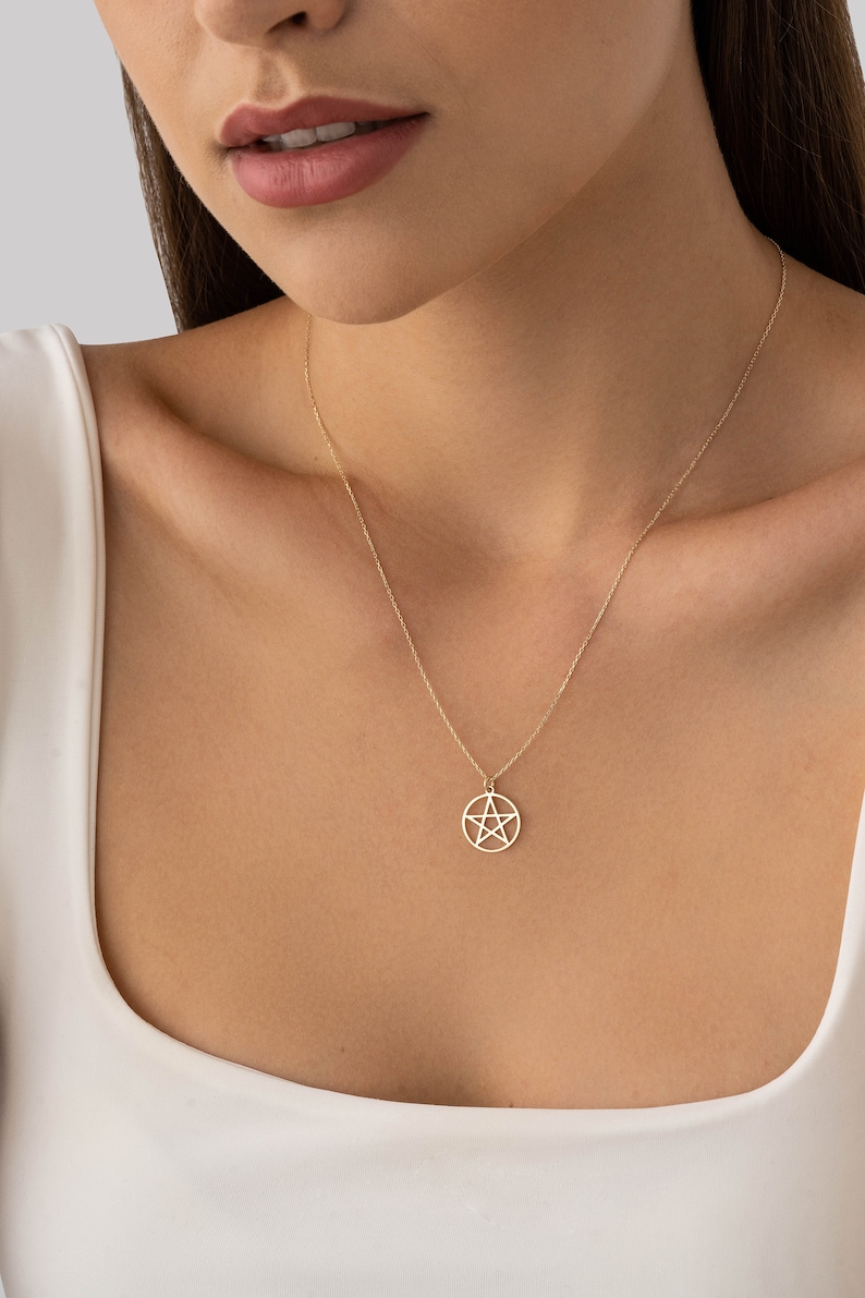 Op de afbeelding: Een gouden ketting met een hanger met een vijfpuntige ster in een cirkel.