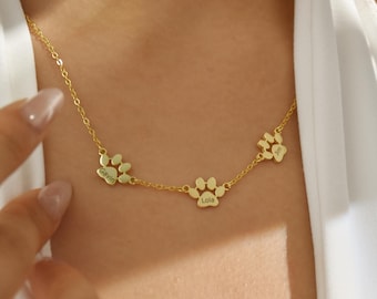 May include: Gold necklace with three paw print charms, each engraved with a name: Gavin, Lola, and Gus.
