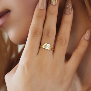 Peut inclure: Une bague en or avec un motif soleil sur le dessus. La bague est portée au doigt d'une personne.