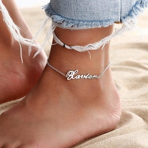 May include: Silver ankle bracelet with the name "Javier" written in cursive.