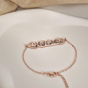 May include: A rose gold bracelet with a charm featuring four engraved dog faces.